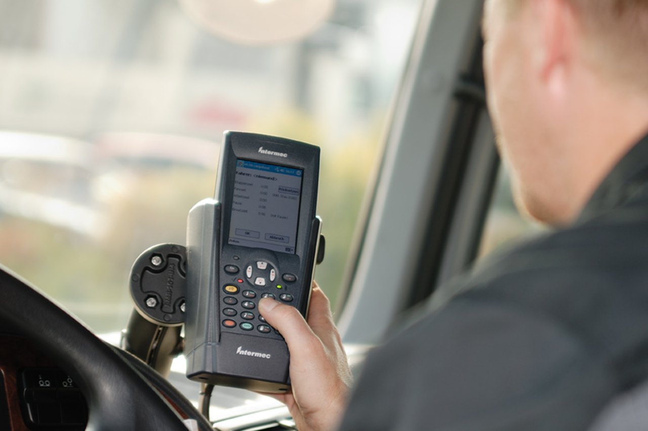 Mann im Fahrzeug bedient ein GPS-Gerät an der Windschutzscheibe.