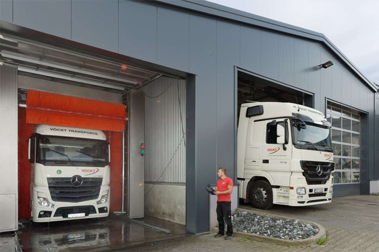 Ein weißer LKW fährt aus einer automatischen Waschanlage, während ein anderer davor wartet.